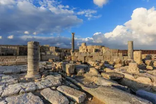 Ancient stone ruins and columns at a historical site in Cyprus under a dramatic sky